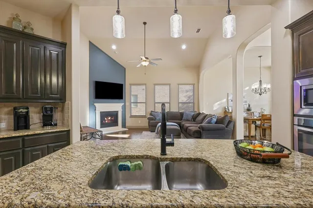 a kitchen with kitchen island granite countertop a sink a counter space appliances and cabinets