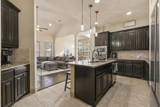 a kitchen with stainless steel appliances granite countertop wooden cabinets a sink dishwasher a stove and a refrigerator