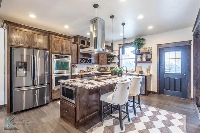 a kitchen with stainless steel appliances granite countertop a refrigerator a stove and a sink