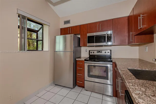a kitchen with granite countertop a sink stainless steel appliances and cabinets