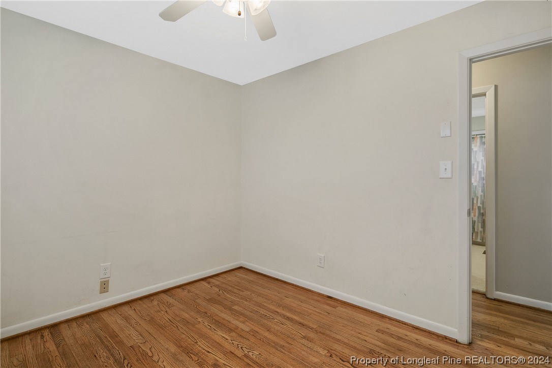 636 Pleasant Loop Fayetteville, NC 28311 - Photo 28 of 40 an empty room with a chandelier fan and wooden floor
