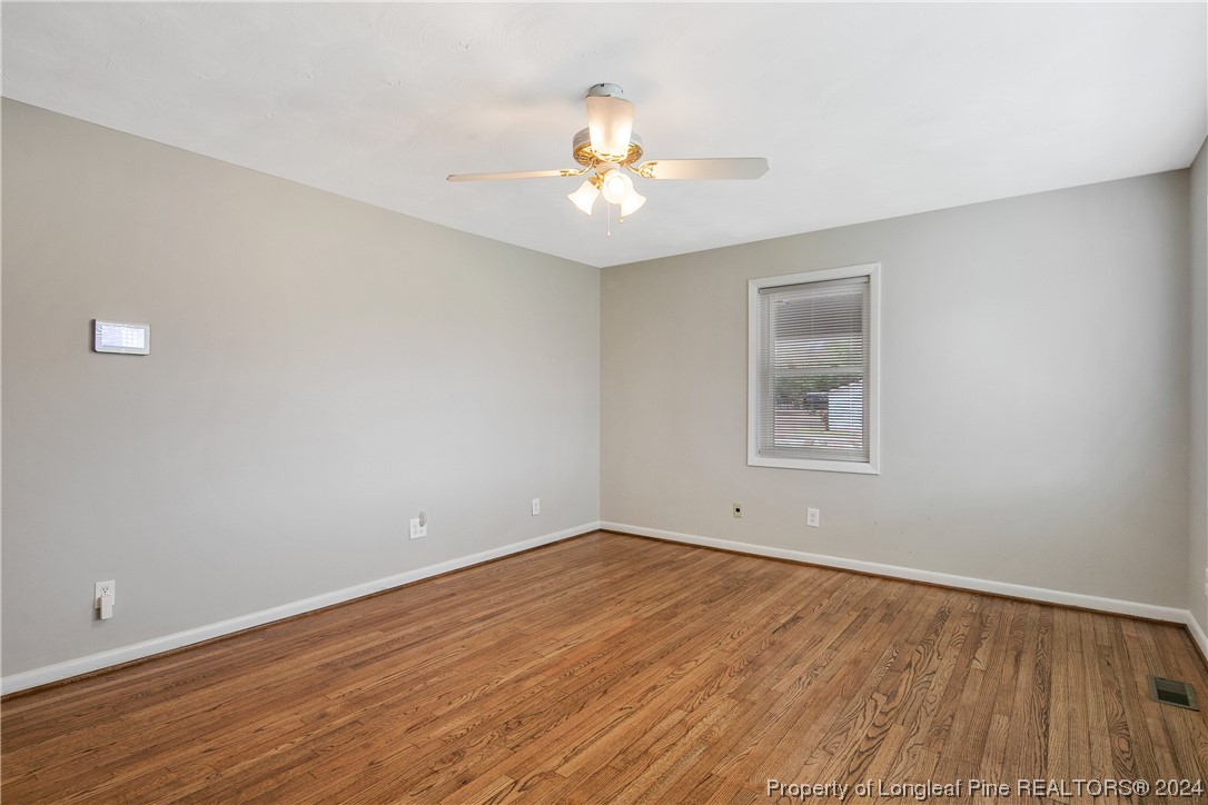 636 Pleasant Loop Fayetteville, NC 28311 - Photo 6 of 40 an empty room with wooden floor chandelier fan and windows