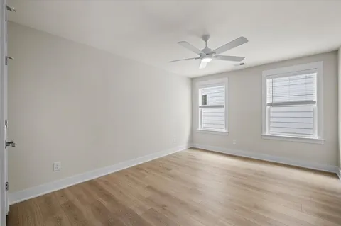 an empty room with chandelier fan and windows
