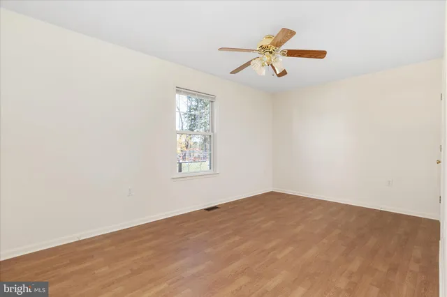 an empty room with windows and ceiling fan