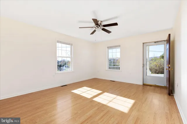 a view of empty room with wooden floor and fan