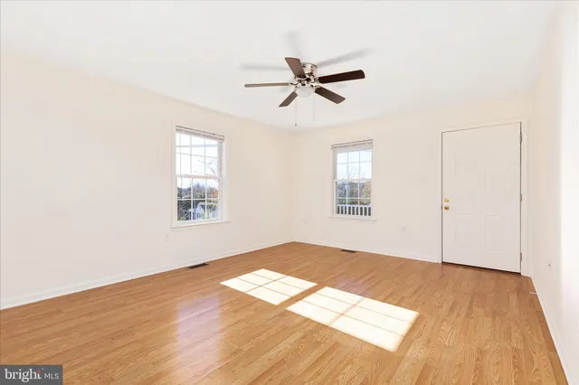 a view of empty room with wooden floor and fan
