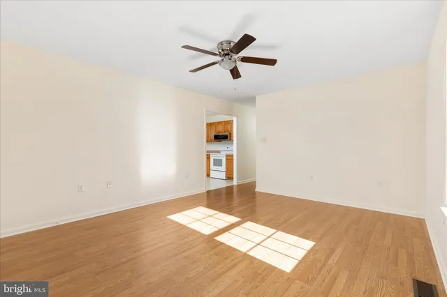 an empty room with wooden floor ceiling fan and windows