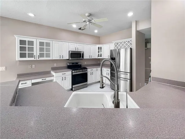 a kitchen with stainless steel appliances a stove a refrigerator a sink a stove a microwave and cabinets