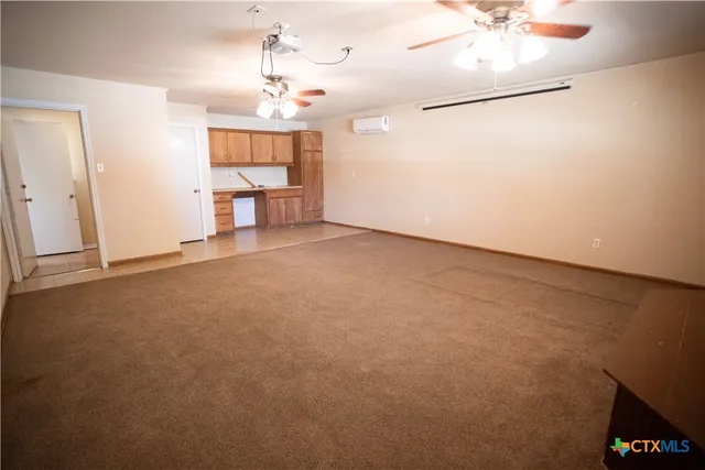 an empty room with a chandelier fan and windows