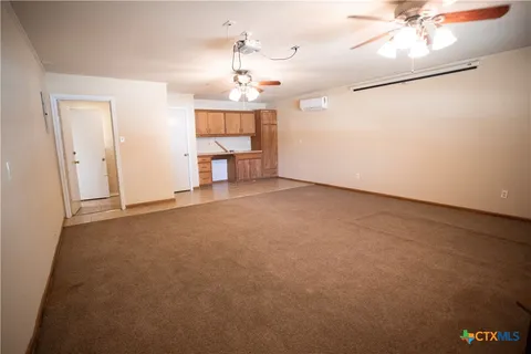 an empty room with a chandelier fan and windows
