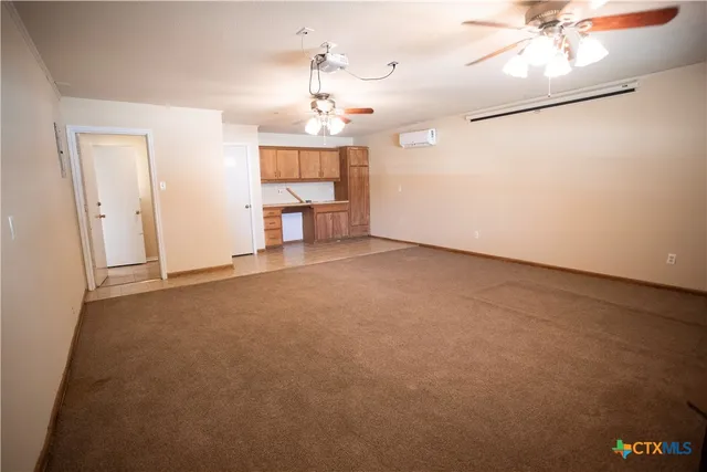 an empty room with a chandelier fan and windows
