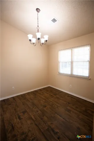 an empty room with wooden floor cabinet and windows