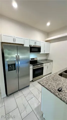 a kitchen with stainless steel appliances granite countertop a sink and a refrigerator