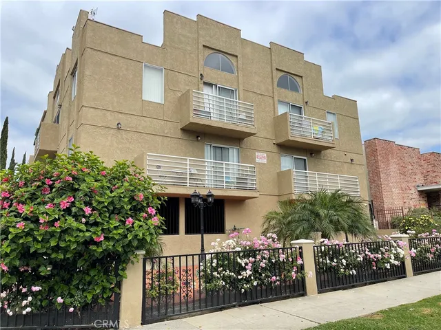 a front view of a multi story residential apartment building with yard and flowers