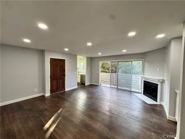 an empty room with wooden floor fireplace and windows