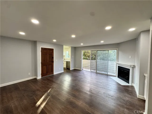 an empty room with wooden floor fireplace and windows
