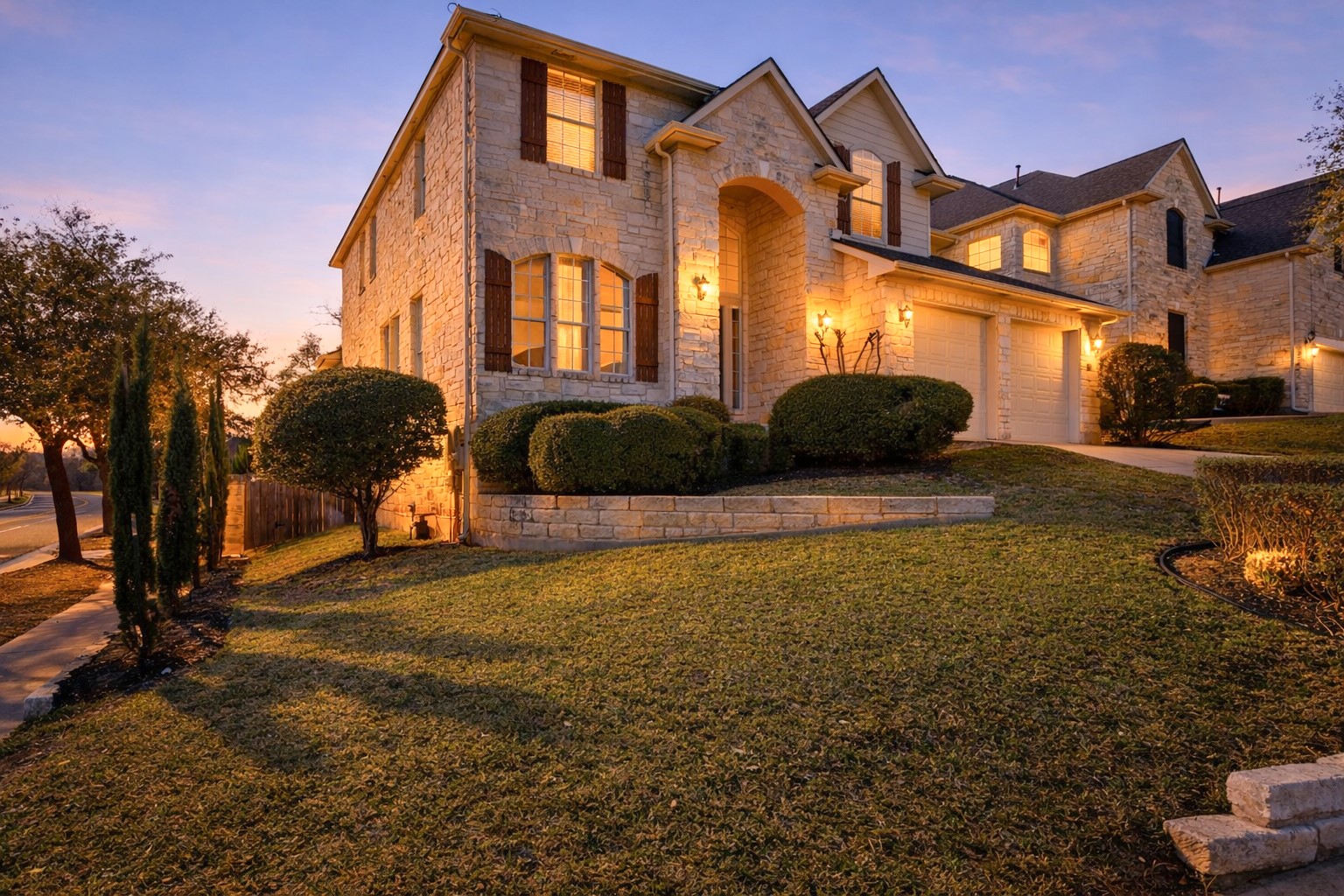 View of front of home with stone siding, a front lawn, concrete driveway, and an attached garage