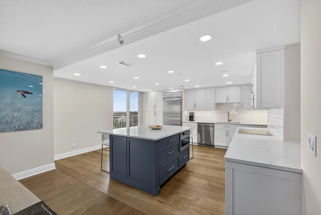 a large kitchen with a large counter top space a sink stainless steel appliances and cabinets