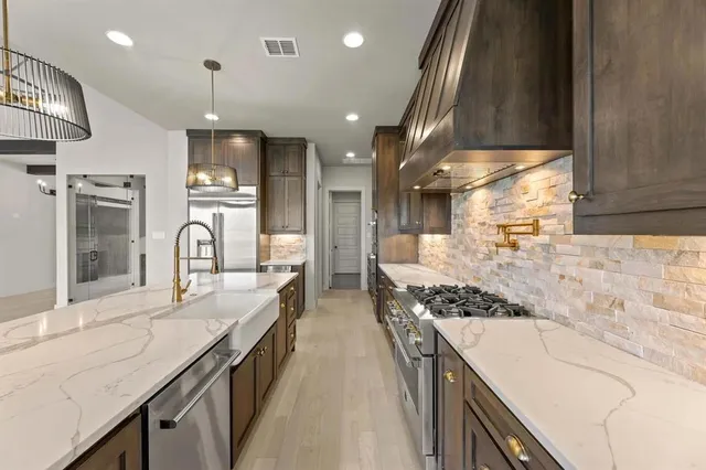 a large kitchen with stainless steel appliances kitchen island granite countertop a large stove a sink dishwasher and cabinets with wooden floor