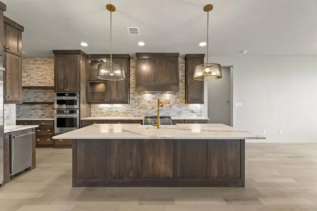 a large kitchen with kitchen island a sink stainless steel appliances and cabinets