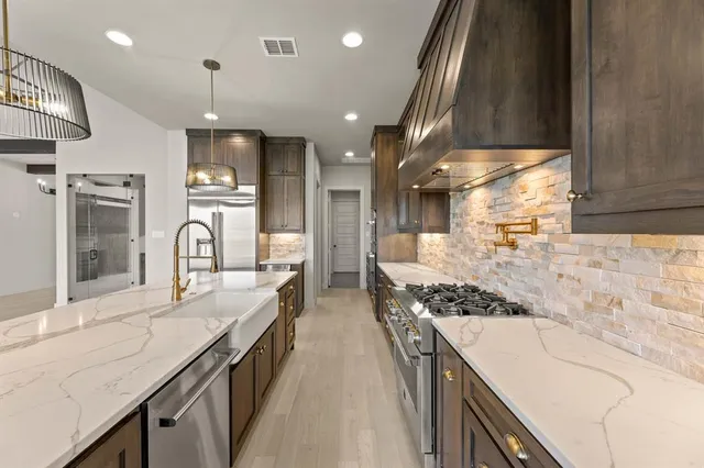 a large kitchen with stainless steel appliances kitchen island granite countertop a large stove a sink dishwasher and cabinets with wooden floor