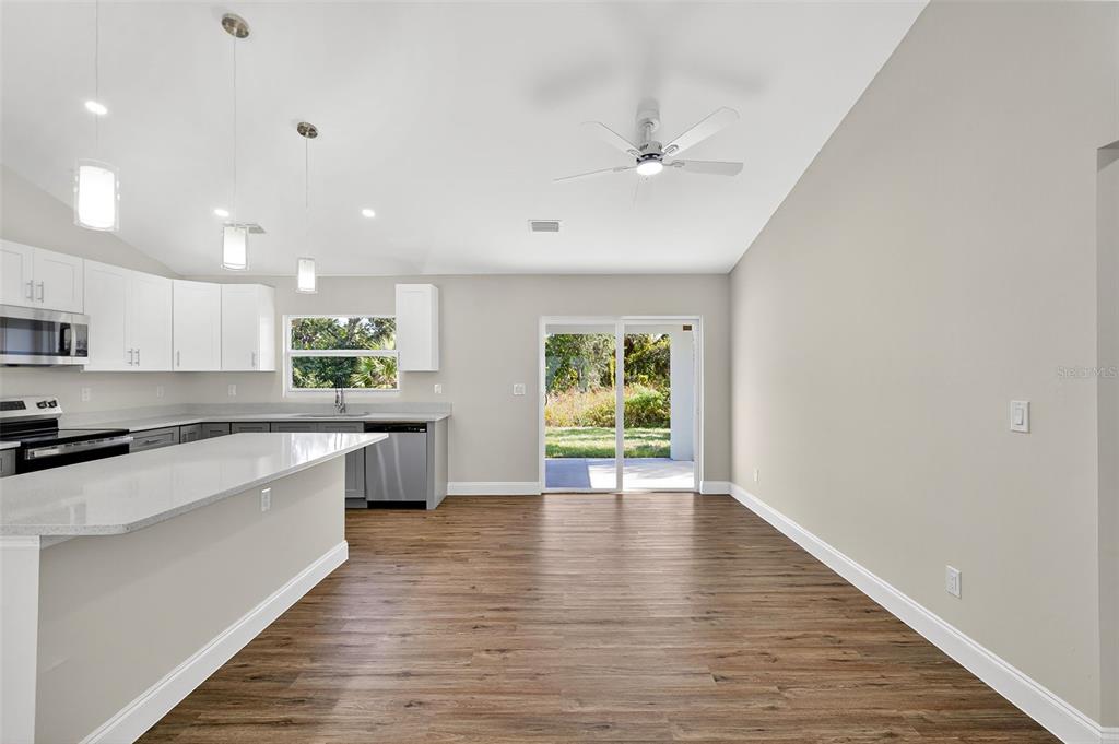 486 Celeste Street Port Charlotte, FL 33954 - Photo 12 of 35 a large kitchen with stainless steel appliances granite countertop a stove top oven a sink dishwasher and white cabinets with wooden floor