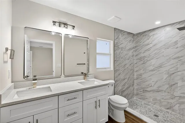 a bathroom with a granite countertop bathtub sink vanity mirror and toilet