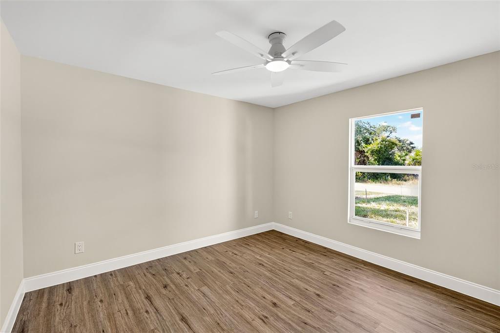 486 Celeste Street Port Charlotte, FL 33954 - Photo 25 of 35 an empty room with wooden floor chandelier fan and windows