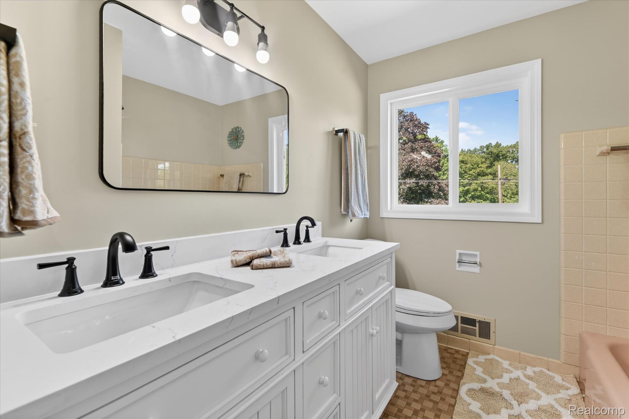 2250 Montague Road Davison, MI 48423 - Photo 25 of 45 Bathroom featuring a dual vanity with white cabinetry and integrated sinks, matte black fixtures, a rectangular wall-mounted mirror, and a large window