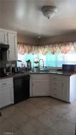 a kitchen with stainless steel appliances kitchen island granite countertop white cabinets and window