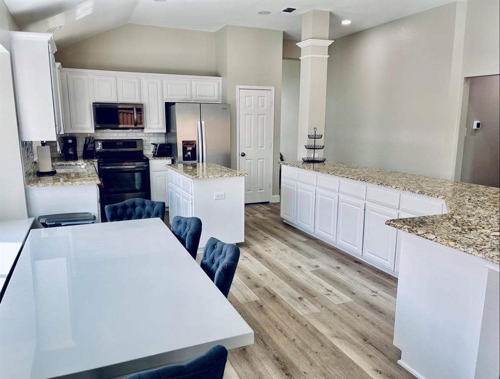 7848 Lancelot Road Frisco, TX 75035 - Photo 12 of 27 a large kitchen with kitchen island white cabinets and stainless steel appliances