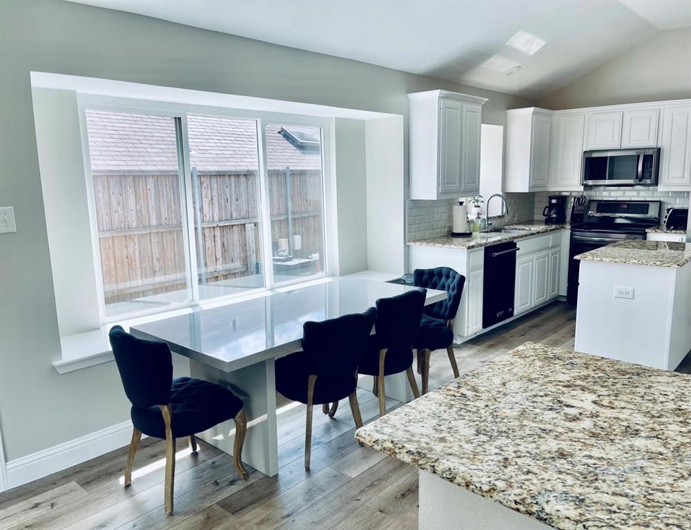 7848 Lancelot Road Frisco, TX 75035 - Photo 14 of 27 a living room with stainless steel appliances kitchen island granite countertop furniture and a wooden floor