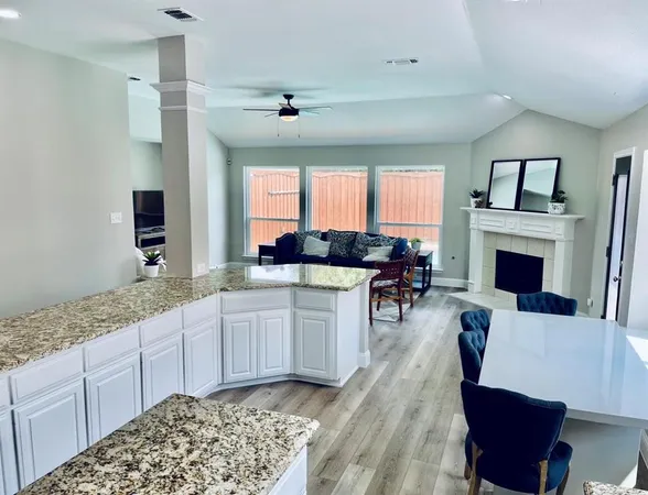 a open kitchen with granite countertop a stove a sink dishwasher and a fireplace with wooden floor
