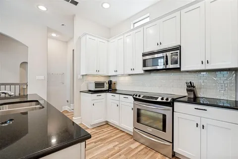 a kitchen with stainless steel appliances granite countertop a stove a sink and white cabinets