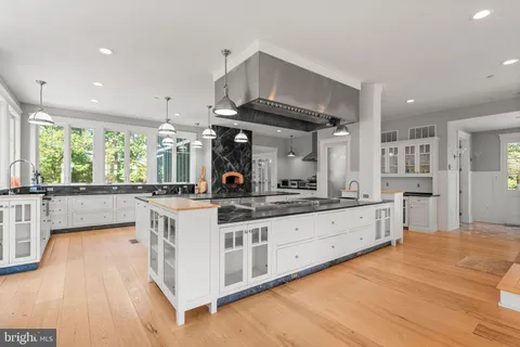 a large kitchen with kitchen island a large counter space a large window and stainless steel appliances