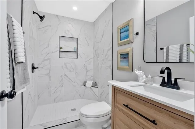 a bathroom with a sink toilet a mirror a vanity and shower