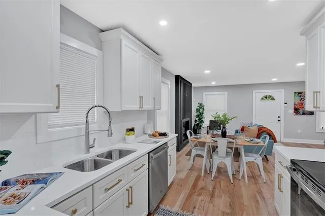 a kitchen with white cabinets a sink dishwasher and a stove with wooden floor