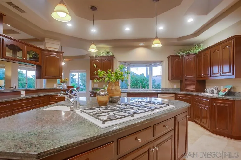 13409 Highlands Ranch Road Poway, CA 92064 - Photo 9 of 24 a kitchen with kitchen island granite countertop wooden cabinets and a counter top space