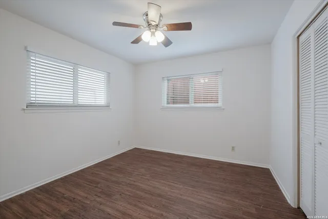 a view of empty room with wooden floor and fan