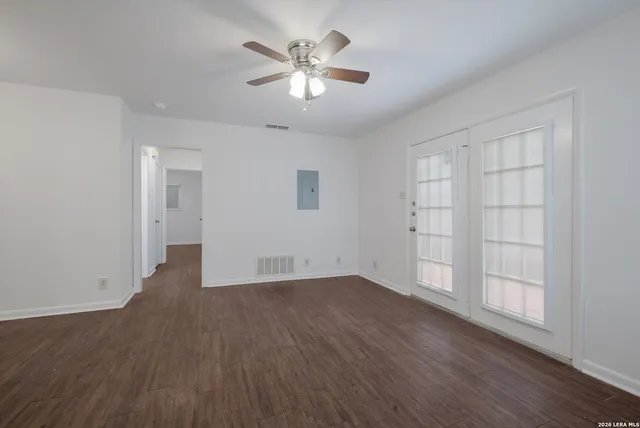 an empty room with wooden floor and windows