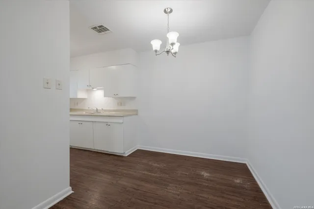 a room with a chandelier fan and wooden floor
