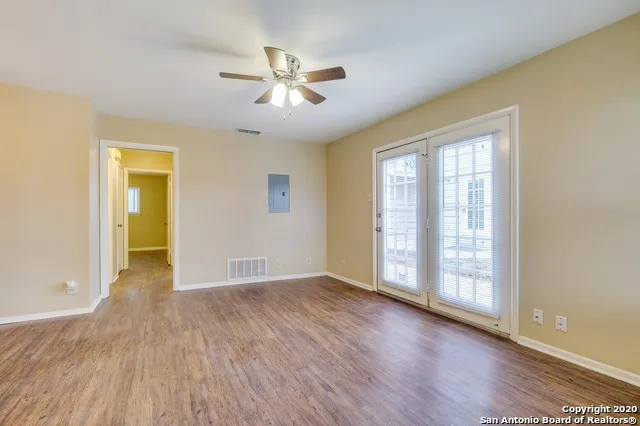 a view of an empty room with wooden floor and a window