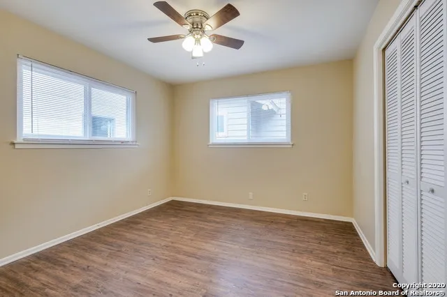 a view of empty room with wooden floor and fan