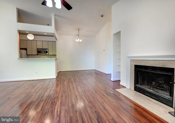 a view of a kitchen and an empty room with wooden floor a fireplace