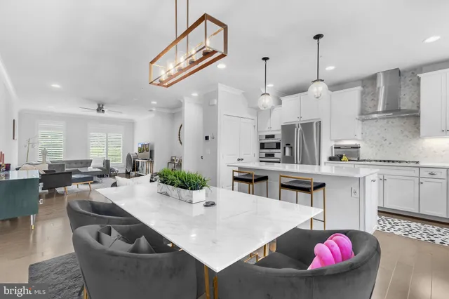 a large kitchen with stainless steel appliances kitchen island granite countertop a living room a stove a sink a couch and white cabinets