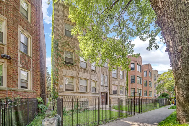 a view of a brick building next to a large tree