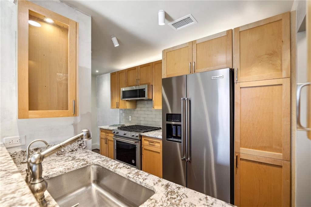 3101 Howell Mill Road Northwest, Unit 121 Atlanta, GA 30327 - Photo 13 of 40 a kitchen with stainless steel appliances granite countertop a refrigerator a sink and a stove