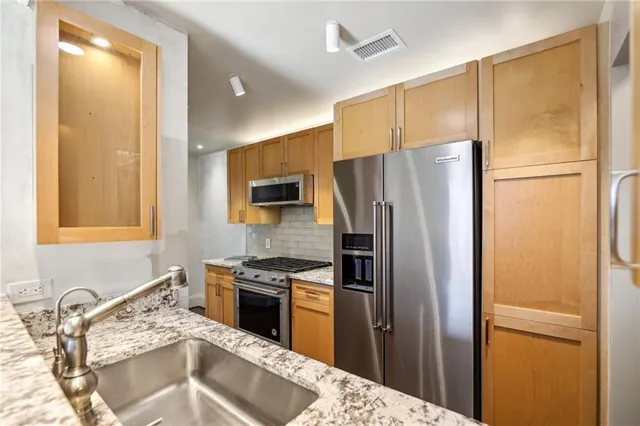 a kitchen with stainless steel appliances granite countertop a refrigerator a sink and a stove