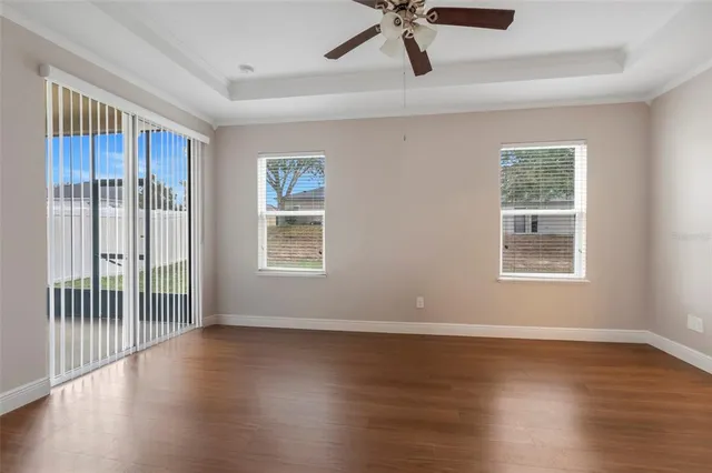 a view of an empty room with wooden floor and a ceiling fan