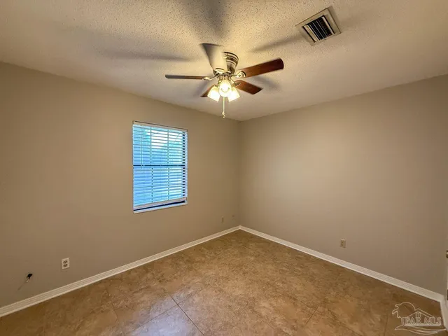 an empty room with a window and a fan
